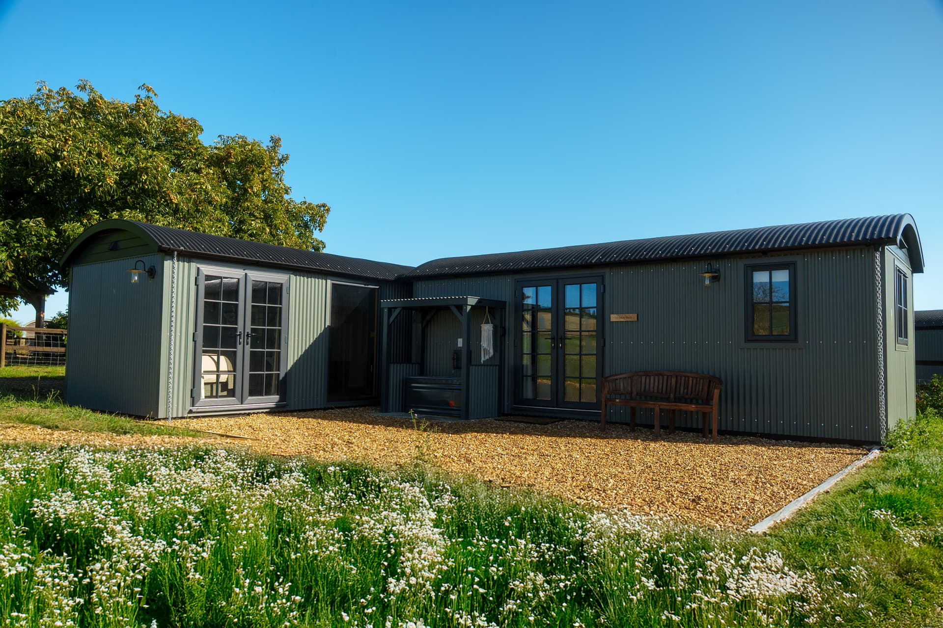 The Baacombe shepherd hut on its iron wheels, the oak gazebo and the Downs behind